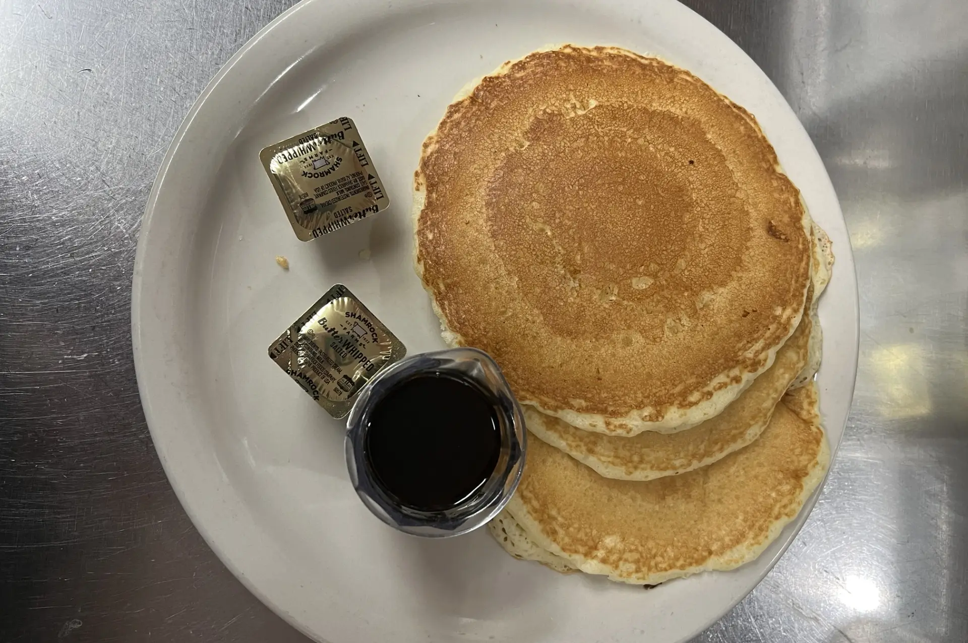 A stack of pancakes  with syrup and chocolate, elegantly presented on a white plate